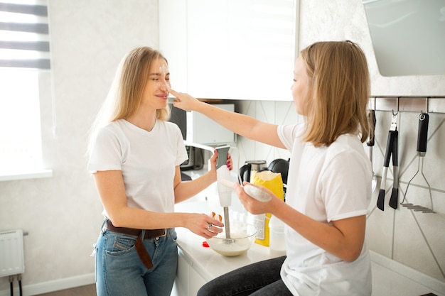 beautiful mom and daughter in the kitchen are engaged in cooking