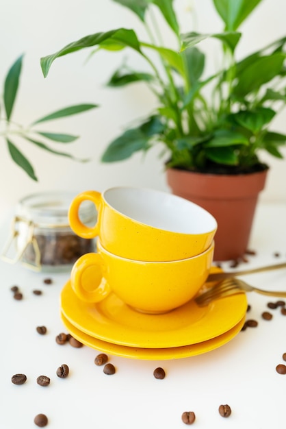 Beautiful morning the process of making coffee An automatic drip coffee maker stands with a yellow cup on a white table scattered coffee beans Green flowerpot on the background