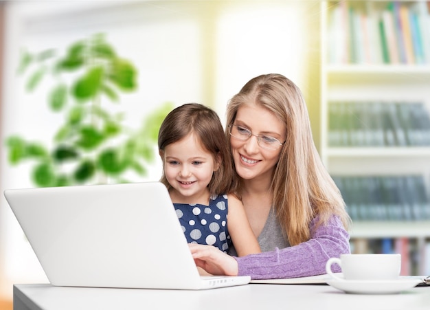 Beautiful mother and cute daughter using laptop