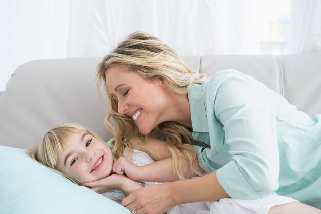 Beautiful mother and daughter lying on the couch