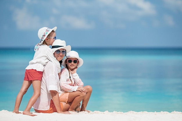 Beautiful mother and her adorable little daughters on the beach