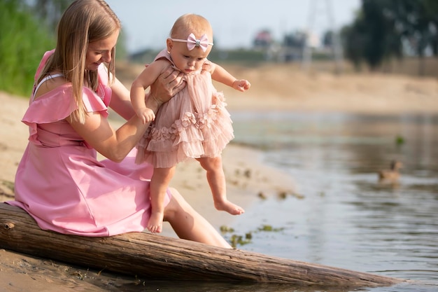 A beautiful mother is walking with her little daughter by the river Motherhood