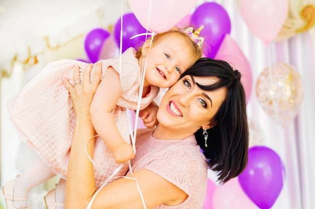 Beautiful mother and little daughter at the celebration of a child's birthday in a restaurant decorated with various decorations