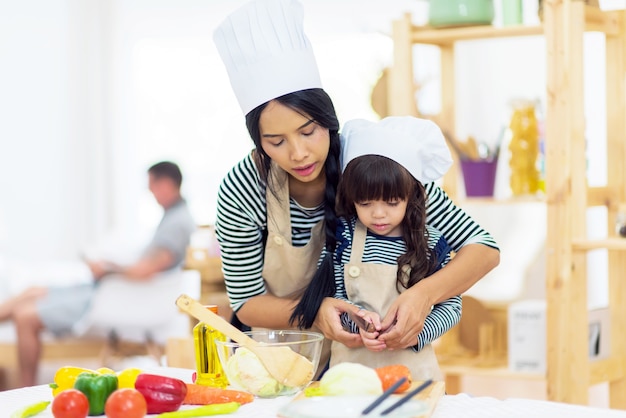 Beautiful mother teaches her daughter hoe to prepare breakfast in the kitchen