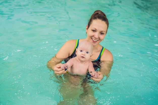 Beautiful mother teaching cute baby girl how to swim in a swimming pool Child having fun in water with mom