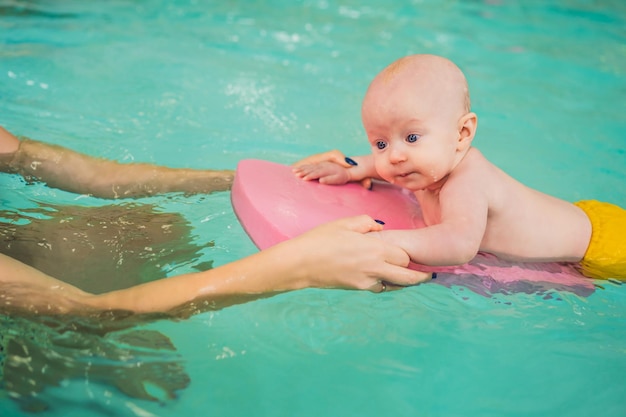 Beautiful mother teaching cute baby girl how to swim in a swimming pool Child having fun in water with mom