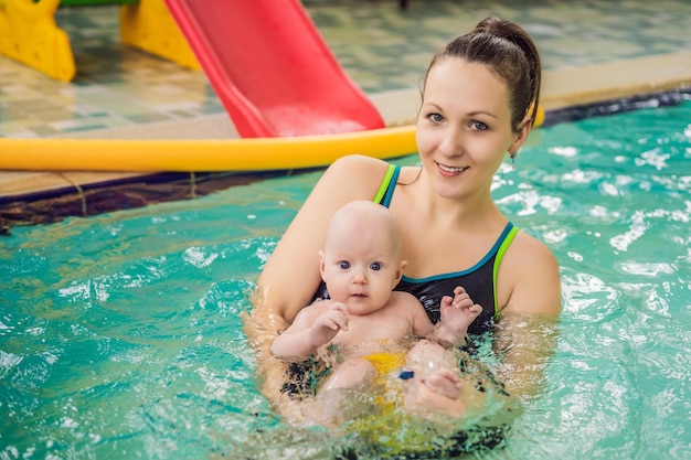 Beautiful mother teaching cute baby girl how to swim in a swimming pool Child having fun in water with mom