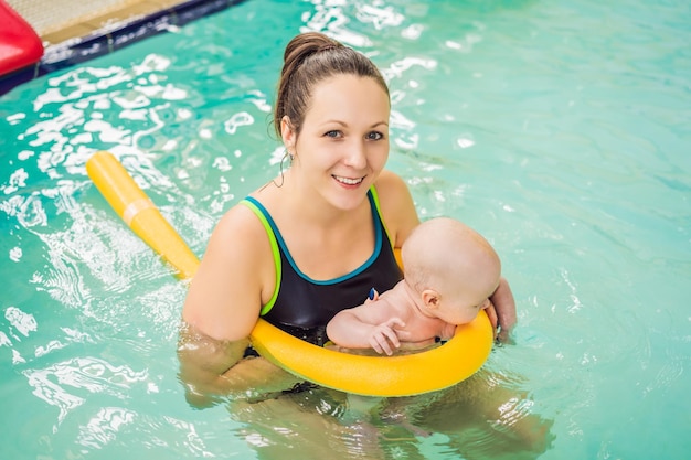 Beautiful mother teaching cute baby girl how to swim in a swimming pool Child having fun in water with mom