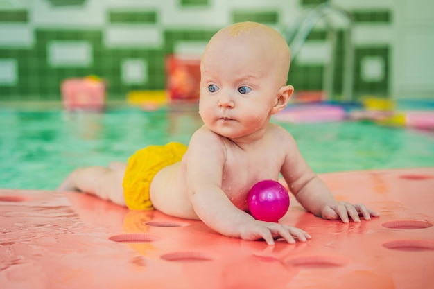 Beautiful mother teaching cute baby girl how to swim in a swimming pool Child having fun in water with mom