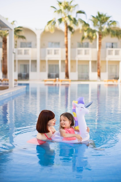 Beautiful mother with her pretty daughter with an inflatable ring in the form of a unicorn