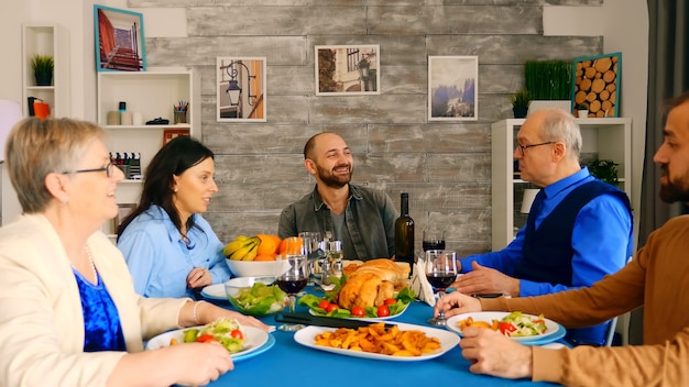 Beautiful multigenerational family having dinner together with delicious food in cozy and bright room