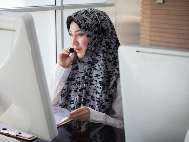 A beautiful Muslim custom service worker smiles with confidence as she advises and assists customers in the workplace