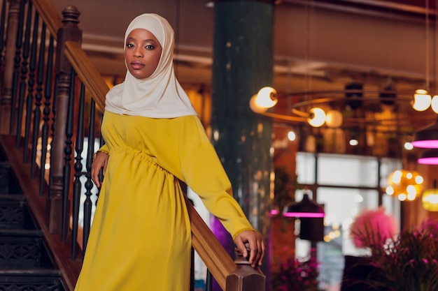 Beautiful Muslim girl in hijab smiling waiting for her food in a restaurant