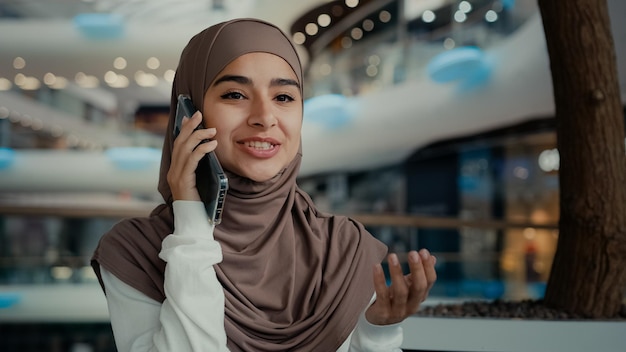 Beautiful muslim woman in hijab sitting in public place talk mobile phone at shopping mall female