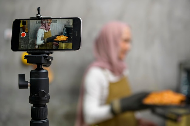 Beautiful muslim woman is making bakery while live streaming or recording video on social media