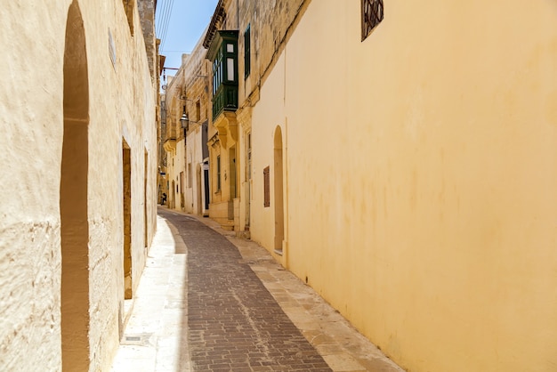 A beautiful narrow lane with typical Maltese architecture. The wall of the building decorated a stone sculpture of saint.