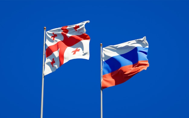 Beautiful national state flags of Georgia and Russia together on blue sky. 3D artwork