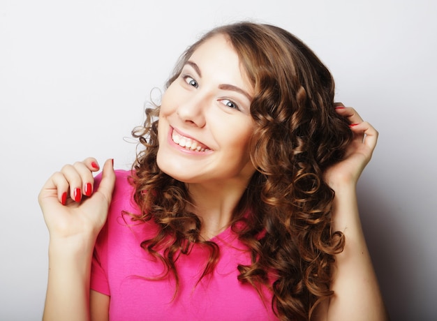 Beautiful natural make-up woman with blond long hair in curly hairstyle smiling at camera