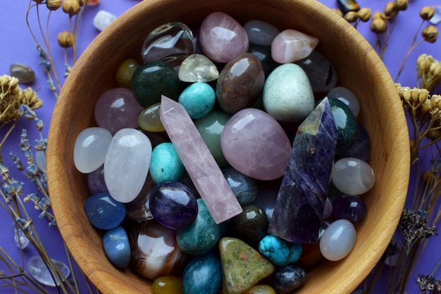 Photo beautiful natural semiprecious stones and dry herbs on a purple background