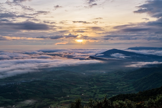 Beautiful nature landscape the sun is above the sea fog that covers the mountains and bright sky during sunrise in the winter at viewpoint of Phu Ruea National Park, Loei province, Thailand.