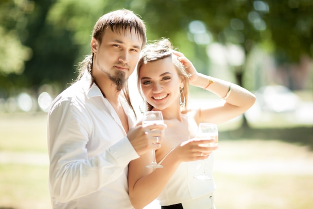 Beautiful newlyweds drinking champagne outdoors 