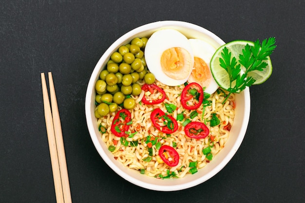 Beautiful noodle dish with green pea eggs red hot pepper and greens