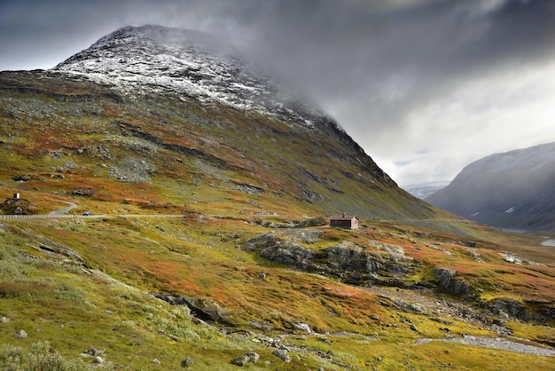 Beautiful Norway landscape under cloudy sky with autumnal colors in mountain with a little chalet