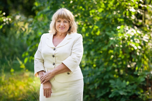 Beautiful old woman in a white suit smiles in the park