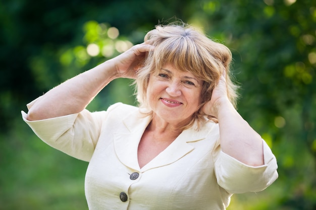 Beautiful old woman in a white suit smiles in the park