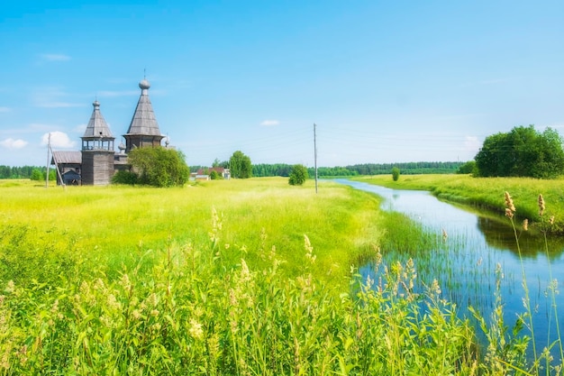 Beautiful old wooden church Church of St John Chrysostom on the river bank in summer in Saunino or Kiprovo Arkhangelsk region