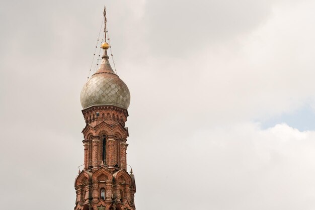 Beautiful orthodox church of red bricks with a dome and crosses against the blue sky