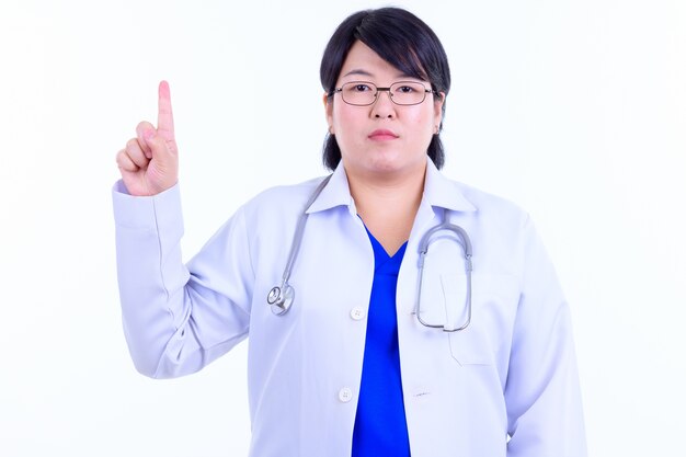  beautiful overweight Asian woman doctor with short hair wearing eyeglasses isolated against white wall