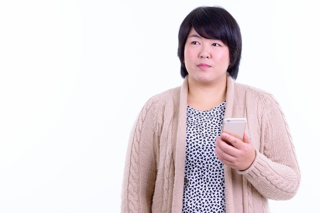 beautiful overweight Asian woman with short hair ready for winter isolated against white wall