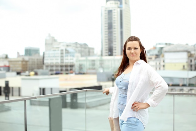 Beautiful overweight woman standing on rooftop in city