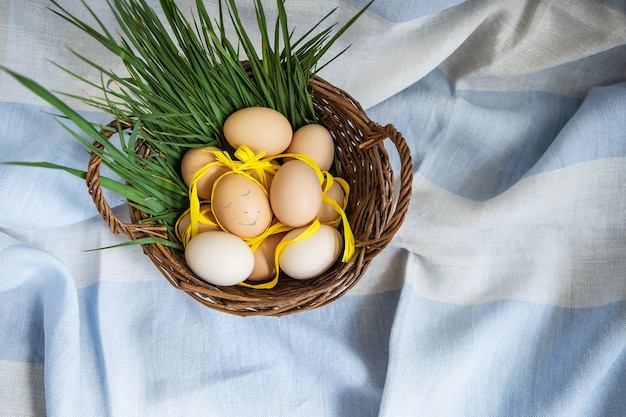 Beautiful painted Easter eggs one egg with a cute face eggs lie in a wooden basket along with green grass Easter postcard