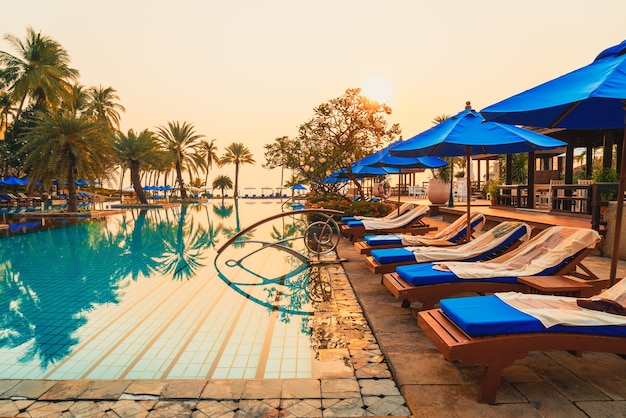 Beautiful palm tree with umbrella chair pool in luxury hotel resort