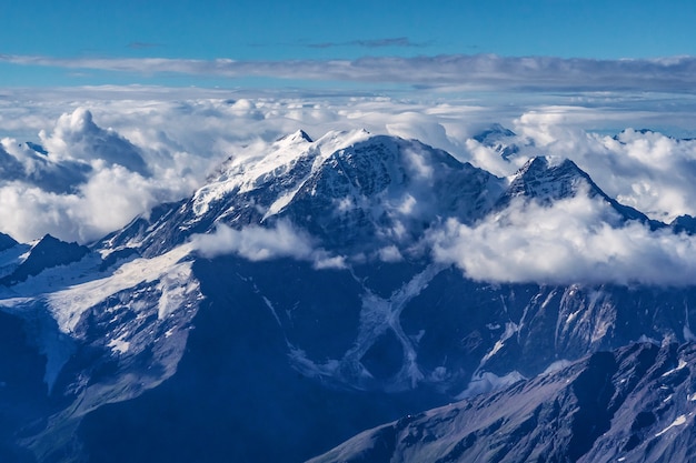 Beautiful panorama of high rocky mountains with mighty glaciers and snowy peaks against the blue sky and clouds