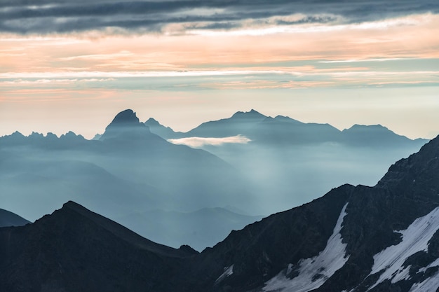 Beautiful panorama of high rocky mountains with mighty glaciers and snowy peaks against the blue sky and clouds