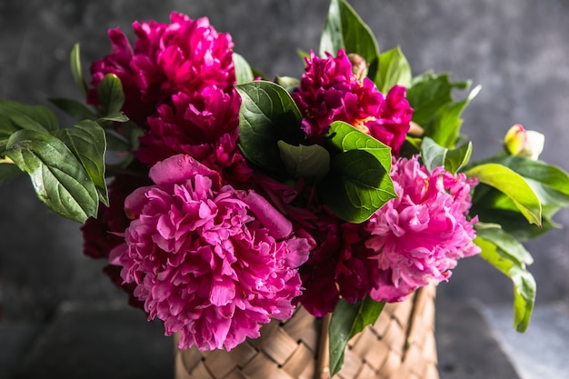 Beautiful peonies in wicker basket on wooden table