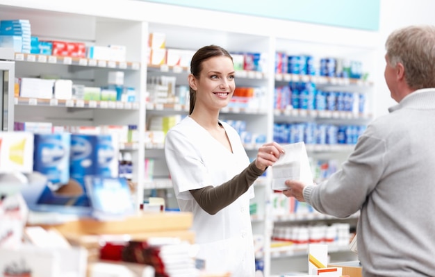 Beautiful pharmacist delivering the package Portrait of beautiful pharmacist giving the package to client at drugstore