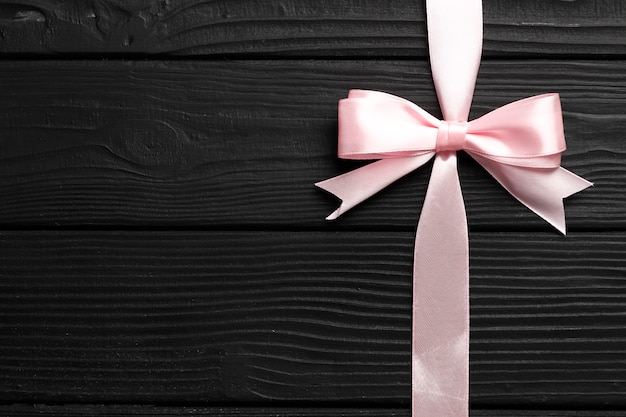 Photo beautiful pink bow and ribbon on black wooden background. congratulations concept.