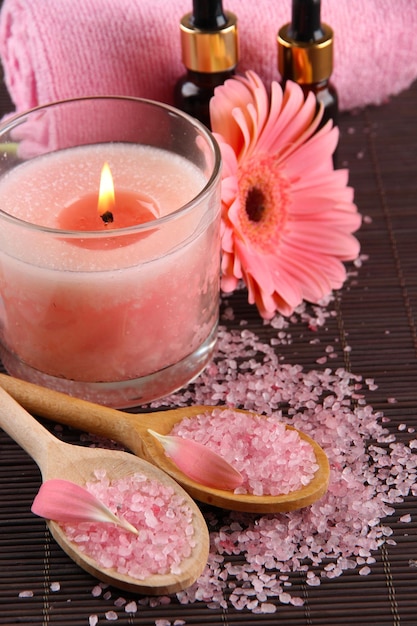 Beautiful pink candle with flower and towel on bamboo mat