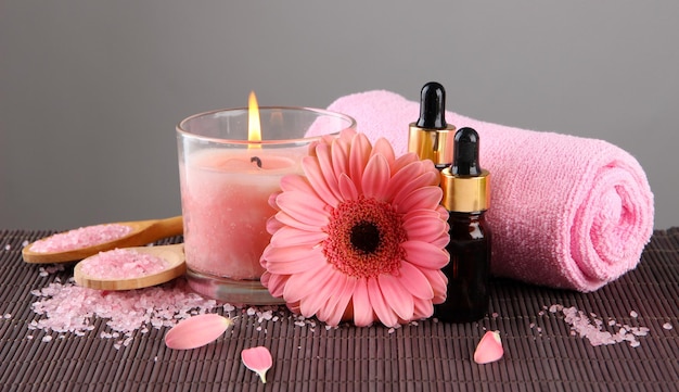 Beautiful pink candle with flower and towel on bamboo mat