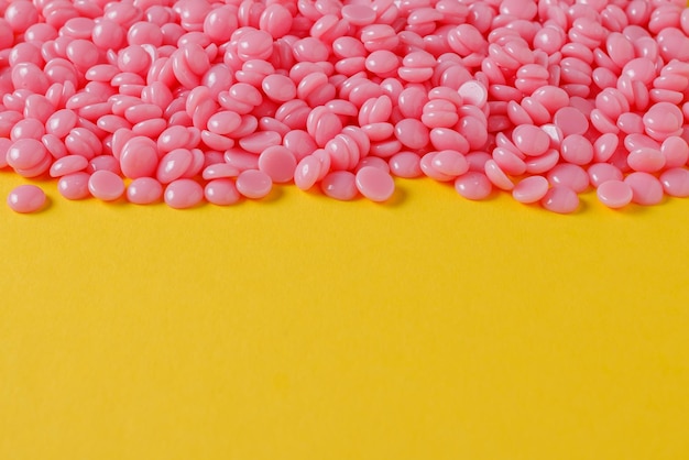 Beautiful pink depilatory wax granules on a yellow background Epilation depilation  Place for text