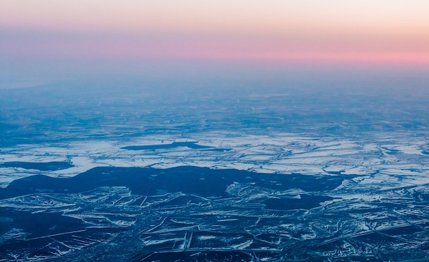 Beautiful pink sunset from above over winter terrain