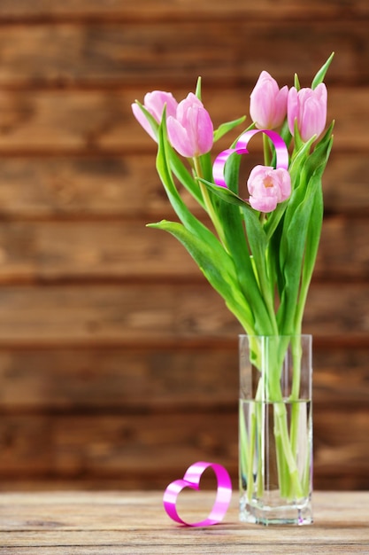 Beautiful pink tulips with decorative heart on wooden background