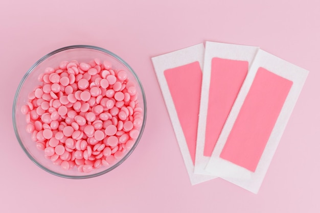 Beautiful pink wax granules and wax depilatory strips on a pink background Epilation depilation