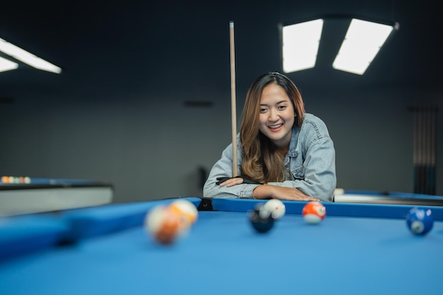 Beautiful pool player smiling while standing crossing hands on the pool at the biliard studio