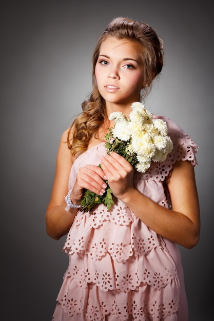 Beautiful portrait of an attractive young girl in a flowering garden Woman with curly hair in a straw hat and white dress New season concept