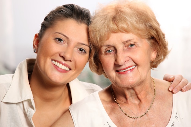 A beautiful portrait of grandma and granddaughter smiling over white background